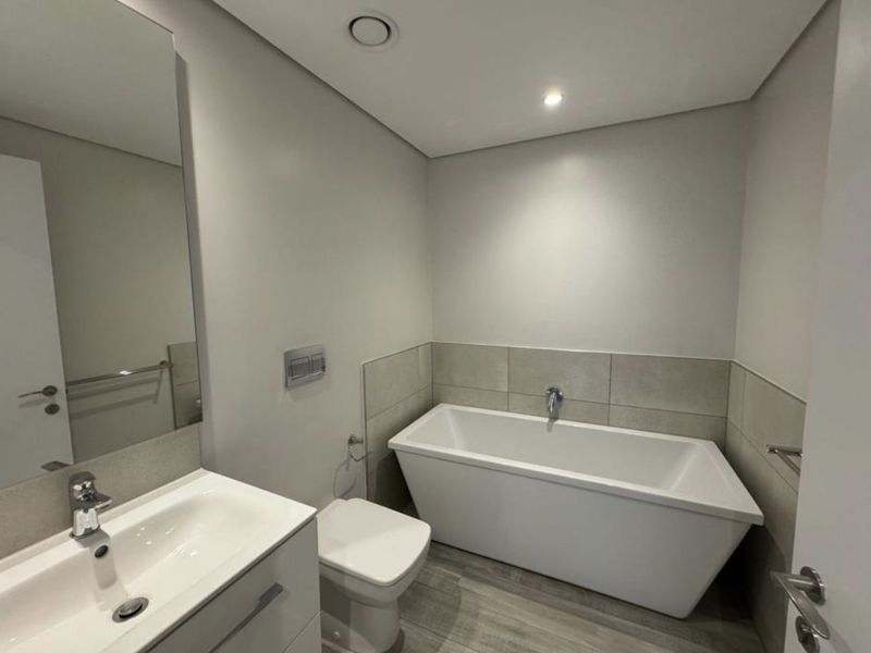A modern, well-maintained bathroom featuring a sleek freestanding bathtub, wall-mounted toilet, and a contemporary vanity unit with a basin.