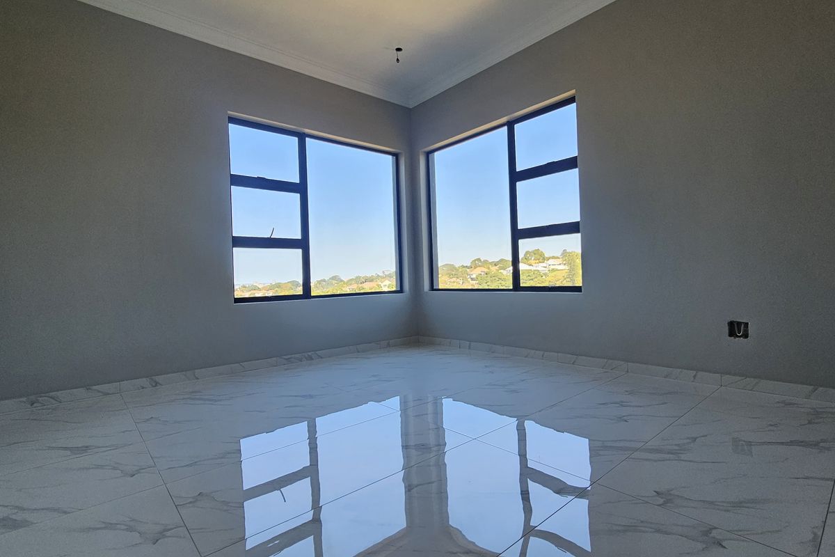 A bright, empty bedroom featuring modern marble-look floor tiles, neutral grey walls, and large corner windows offering expansive views.