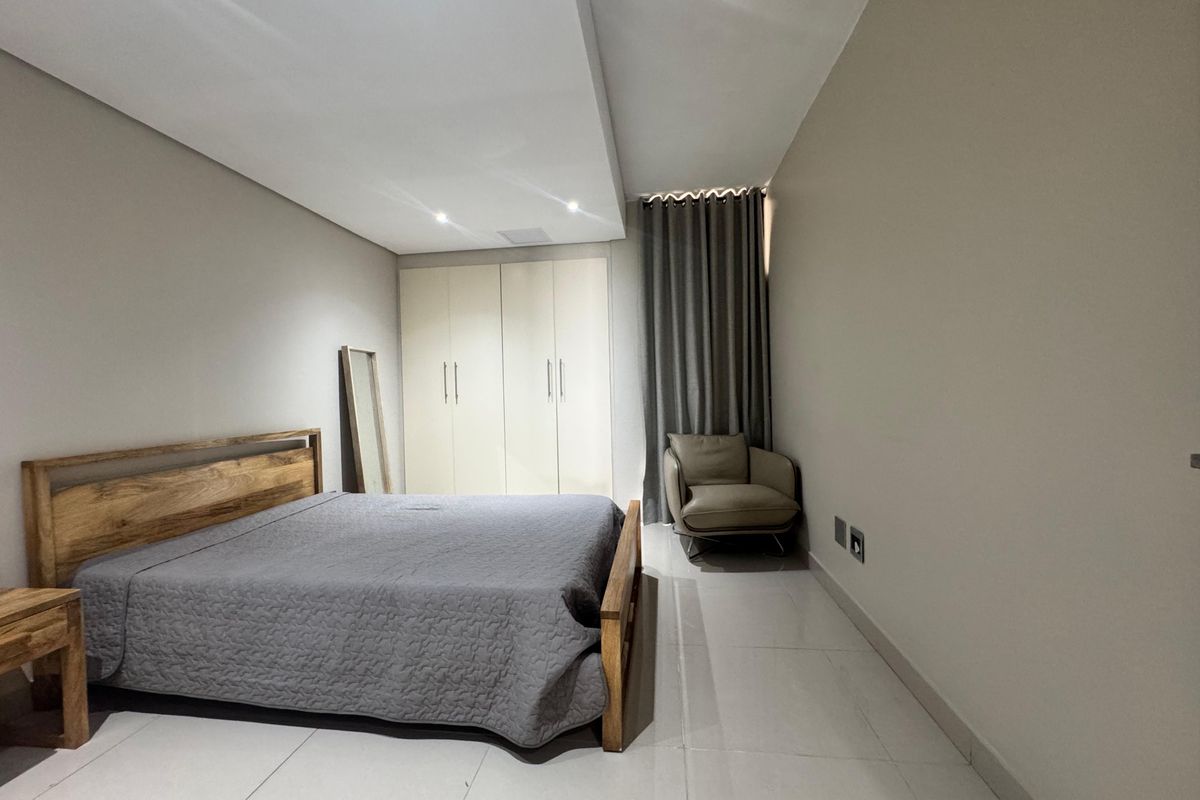 A well-maintained bedroom featuring built-in wardrobes, recessed ceiling lighting, and neutral tiled flooring.