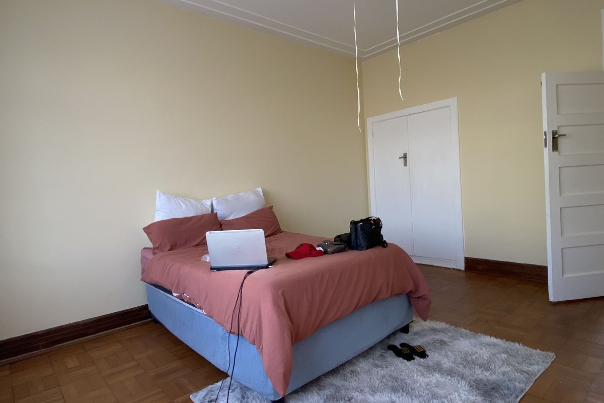 A bedroom featuring original parquet flooring, built-in cupboard, and neutral wall finishes.