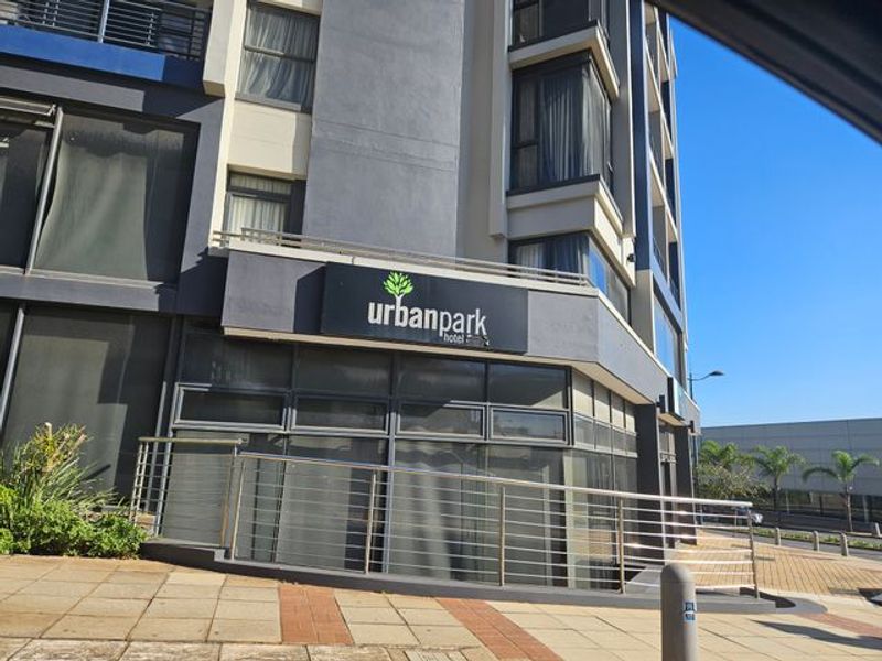 Exterior view of the Urban Park Hotel building featuring a modern glass facade, stainless steel balustrades, and paved pedestrian access.