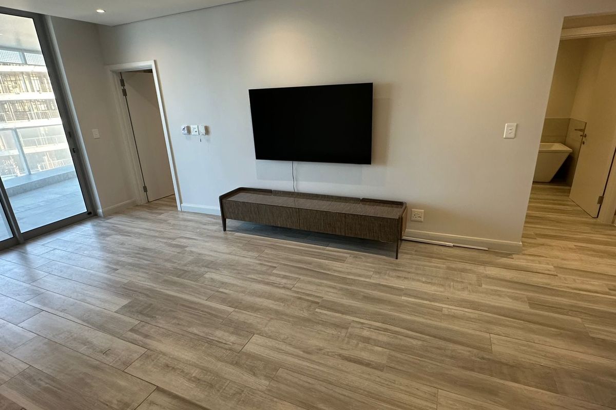 Modern living area featuring light wood-look tile flooring, recessed ceiling lighting, and direct access to a private balcony.