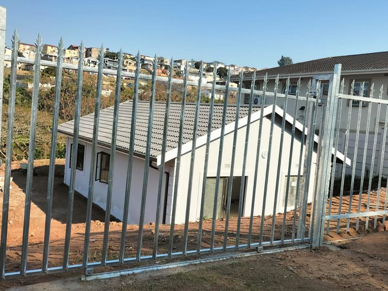 Rear view of a residential house featuring a tiled roof, sliding glass door, and secure galvanized steel palisade fencing surrounding the unlandscaped yard.
