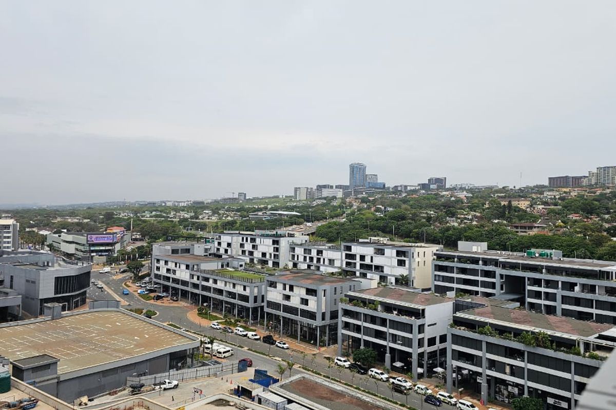 An elevated aerial view overlooking a modern urban development with contemporary apartment blocks and surrounding commercial infrastructure.