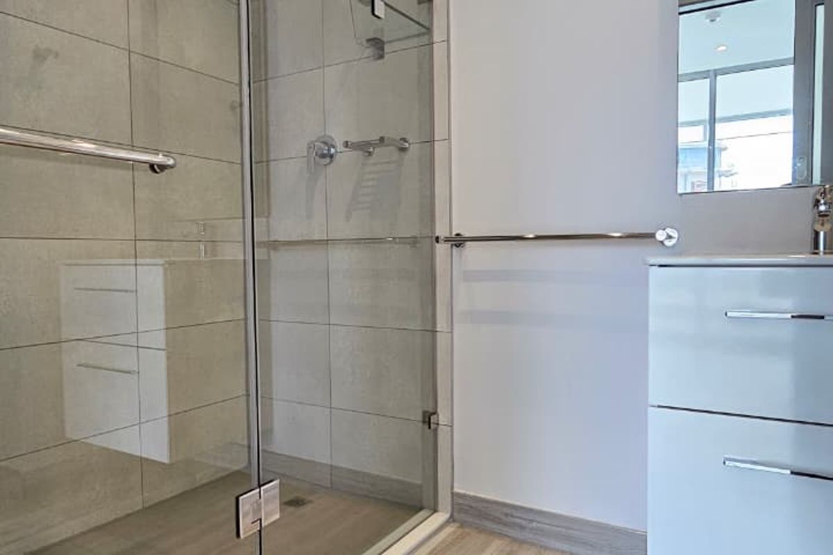 Modern bathroom featuring a frameless glass walk-in shower, contemporary vanity unit, and neutral floor tiling.