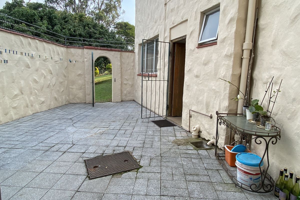 A private rear courtyard featuring paved flooring, a secure arched gate, and direct access to the townhouse interior.