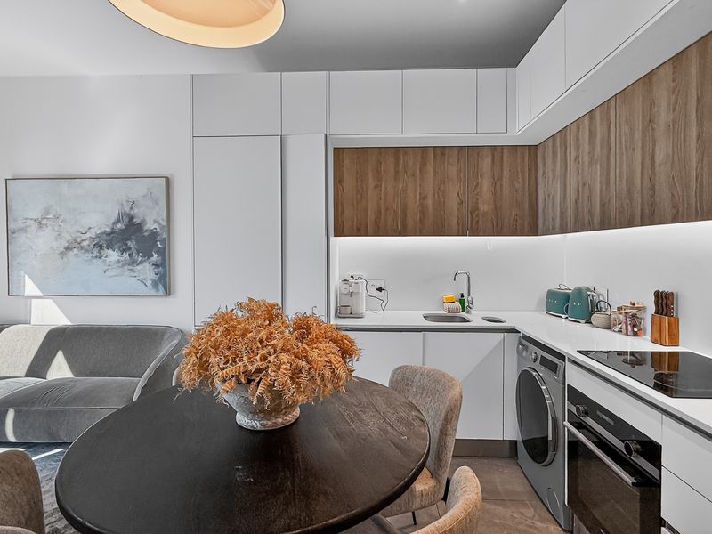 Modern open-plan kitchen featuring sleek white and wood-grain cabinetry, integrated appliances, and a clean, minimalist aesthetic seamlessly connected to the living area.