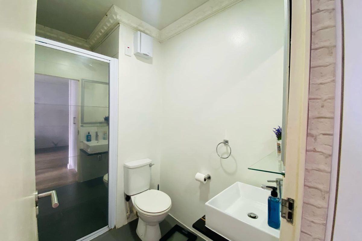Compact bathroom featuring a modern vessel sink, wall-mounted toilet, and a glass-enclosed shower area with neutral finishes.