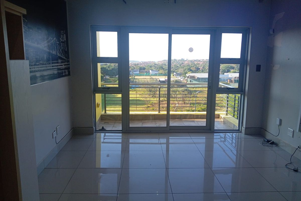 Bright living area featuring large sliding glass doors leading to a balcony with scenic views and polished floor tiles throughout.