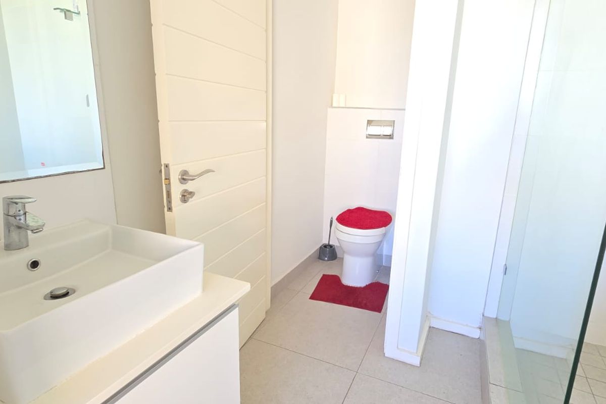 Modern bathroom featuring a floating vanity with basin, a wall-mounted toilet, and a glass-enclosed shower with tiled flooring.
