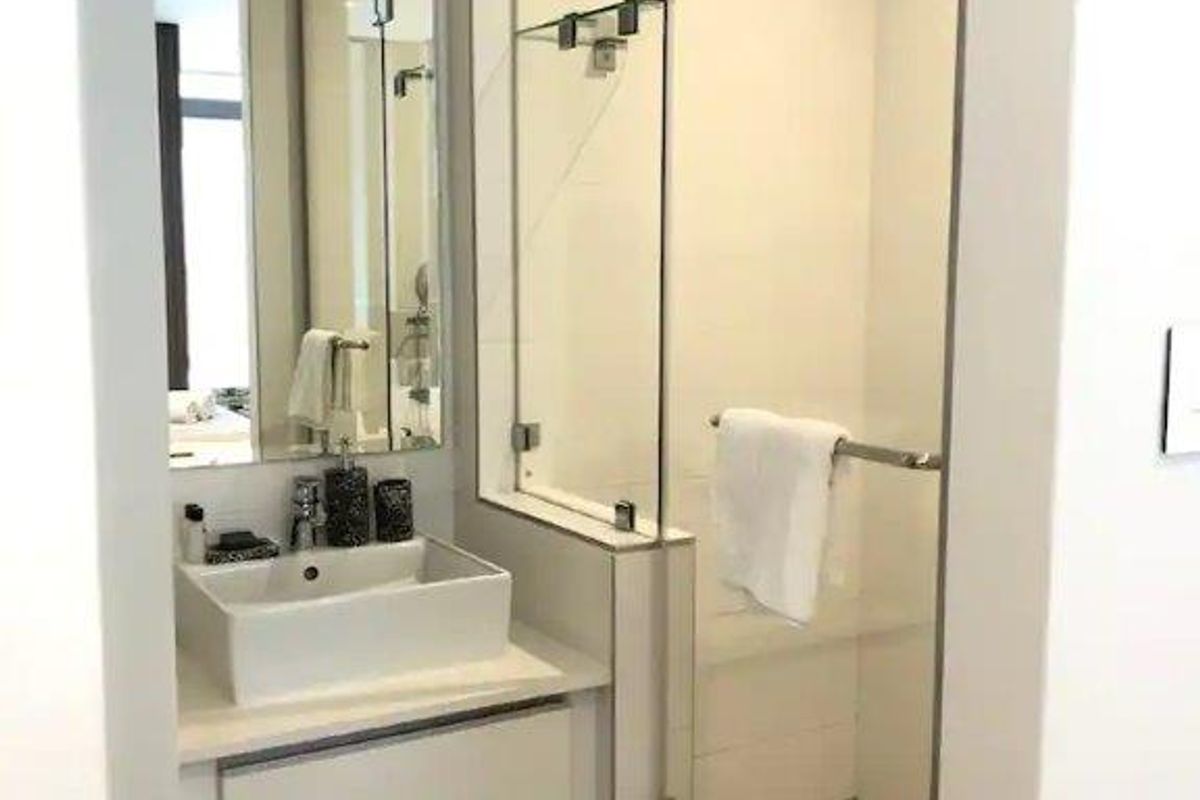 Modern bathroom featuring a vessel sink vanity, glass-enclosed shower with wall-mounted showerhead, and neutral tiled finishes.