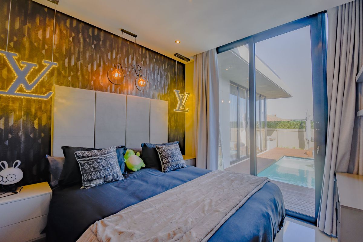 Modern bedroom featuring a large upholstered headboard, feature wallpaper, and floor-to-ceiling sliding glass doors opening directly onto a private pool deck.