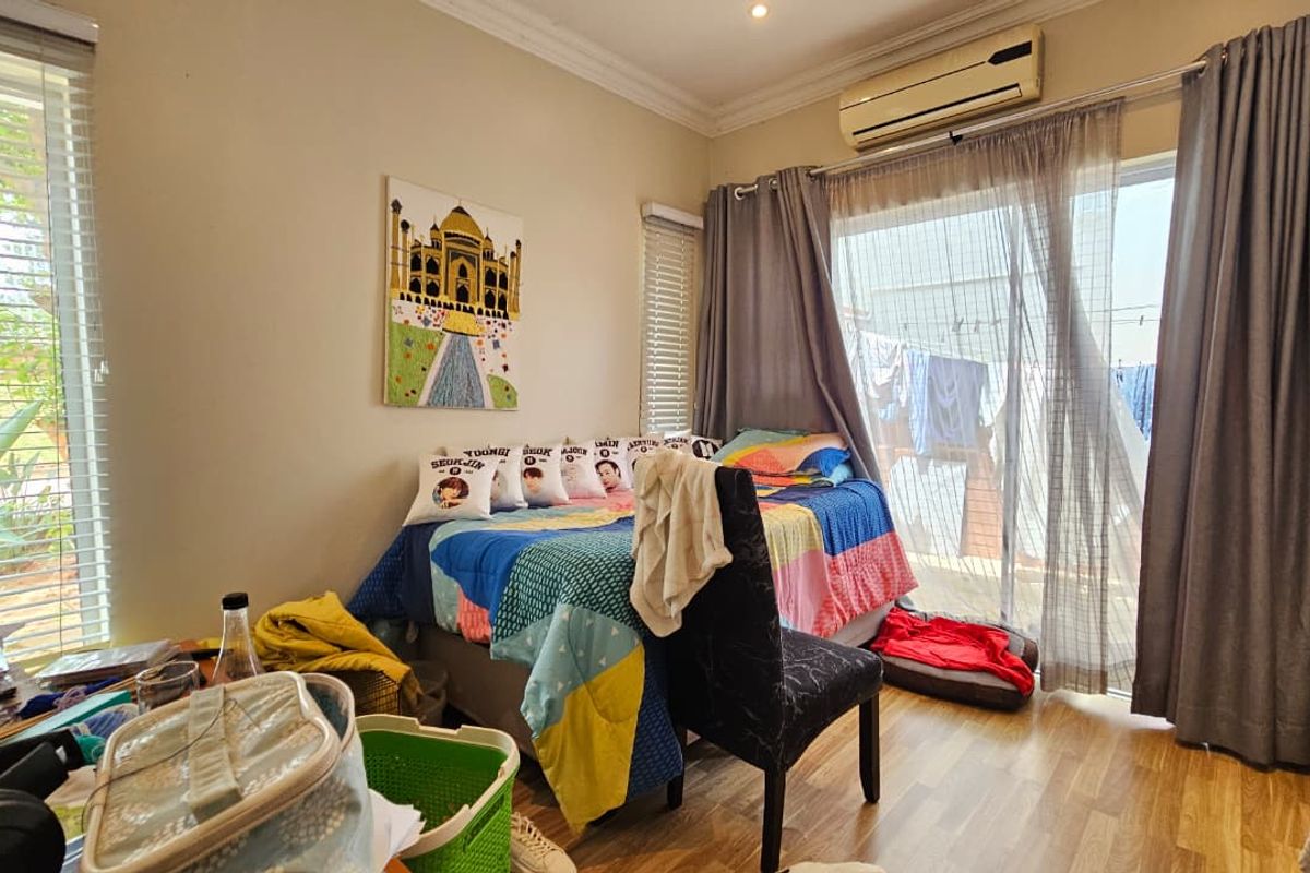 A bedroom featuring laminate flooring, a wall-mounted air conditioning unit, and sliding glass doors providing access to an outdoor area.