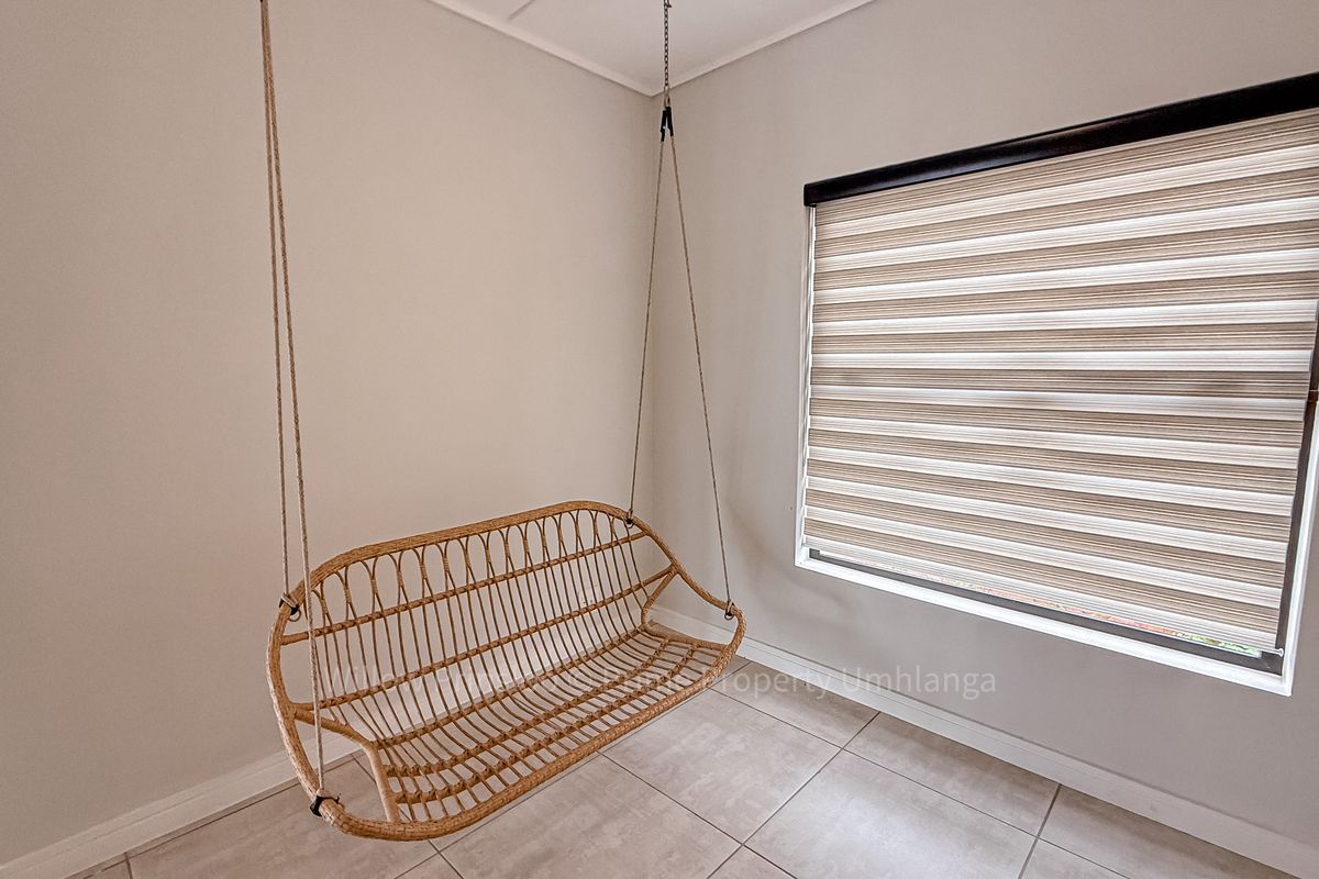 A bright, neutral-toned room featuring modern tiled flooring and a contemporary dual-layer roller blind on the window.