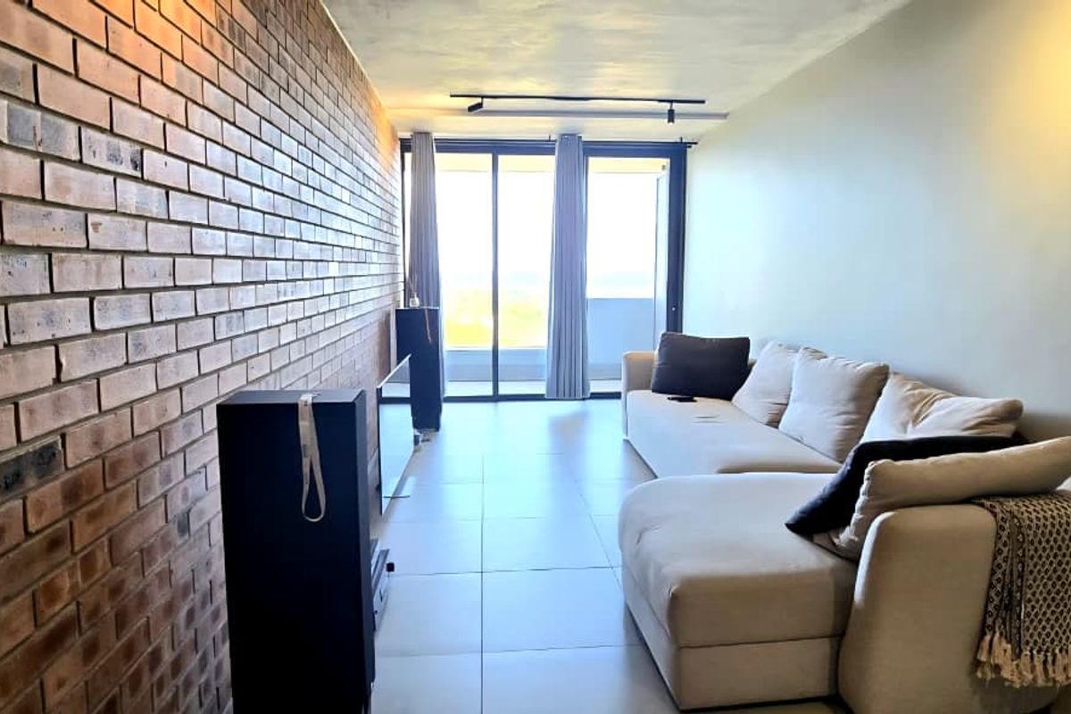 Modern living room featuring an exposed brick accent wall, large format floor tiles, and sliding glass doors leading to a balcony.