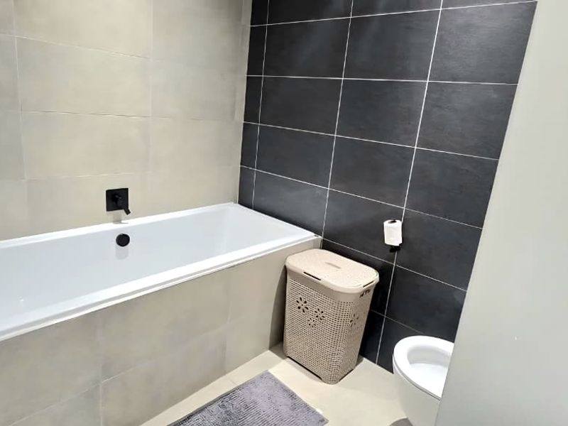 Modern bathroom featuring a built-in bathtub with matte black fixtures and contrasting light and dark ceramic wall tiles.
