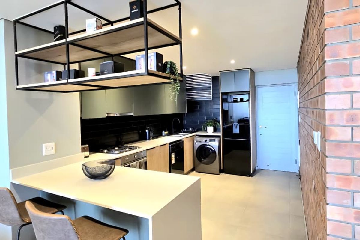 Modern kitchen featuring a breakfast bar, built-in appliances, sleek cabinetry, and a striking exposed brick feature wall.