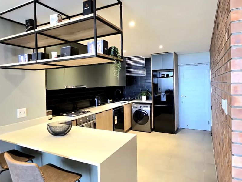 Modern kitchen featuring a breakfast bar, built-in appliances, sleek cabinetry, and a striking exposed brick feature wall.