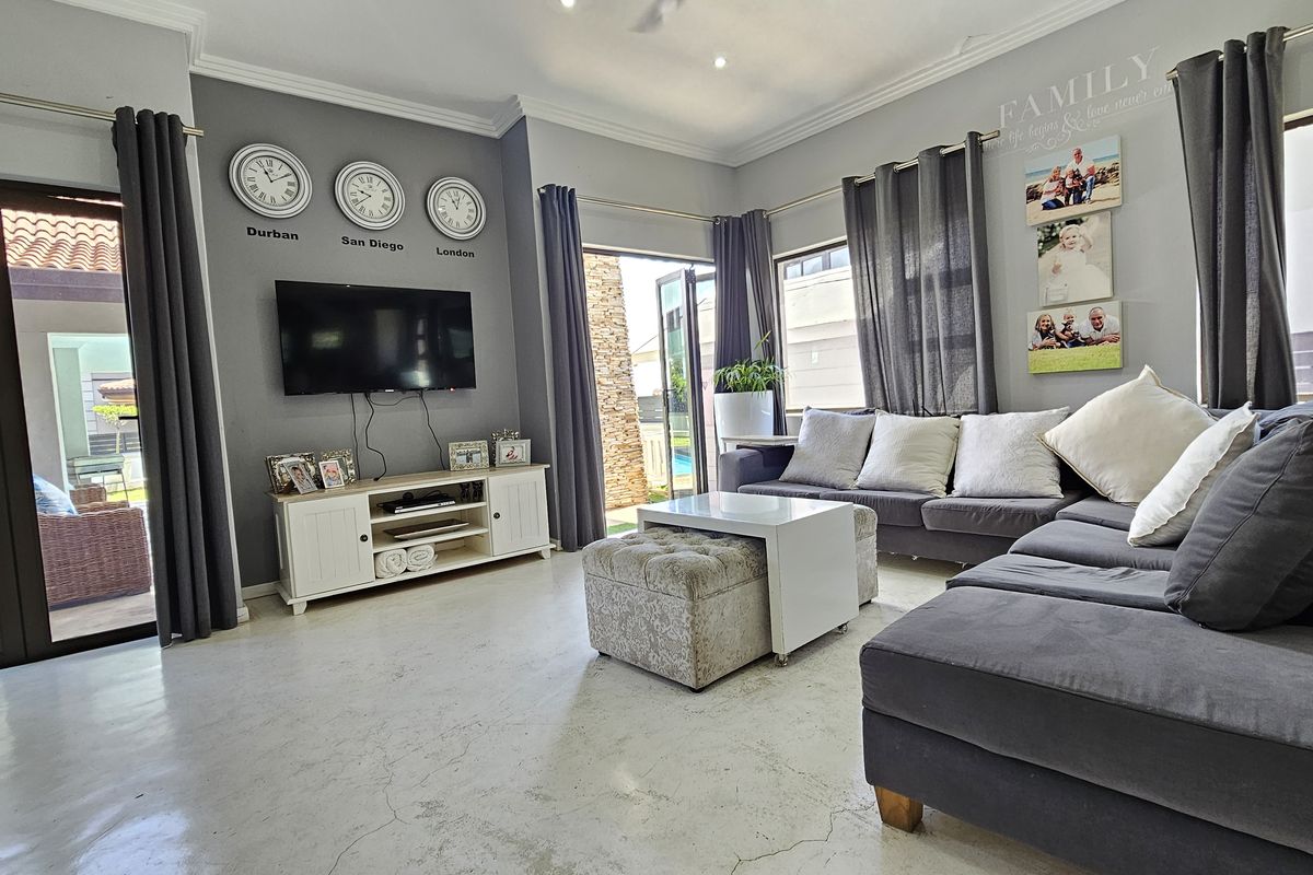 A spacious living room featuring polished concrete floors, recessed ceiling lighting, and large glass sliding doors providing access to the outdoor patio area.