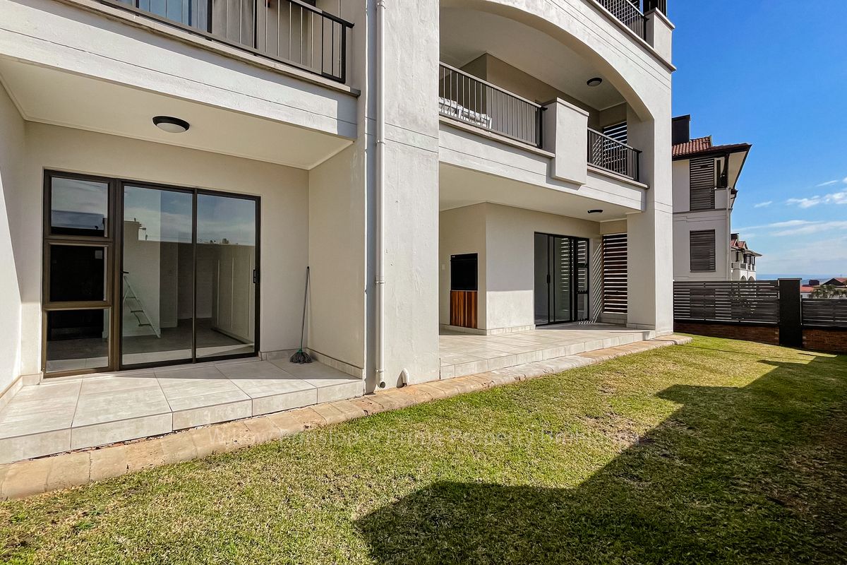 A ground floor apartment featuring a tiled patio with a built-in braai, overlooking a private garden area with modern architectural finishes.