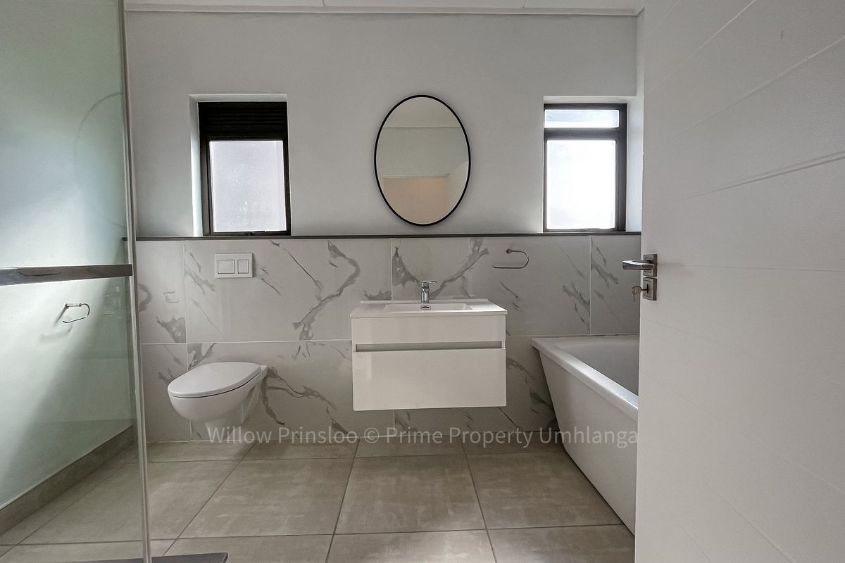 Modern bathroom featuring a wall-mounted vanity, floating toilet, glass-enclosed shower, and a bathtub with marble-look wall tiling.