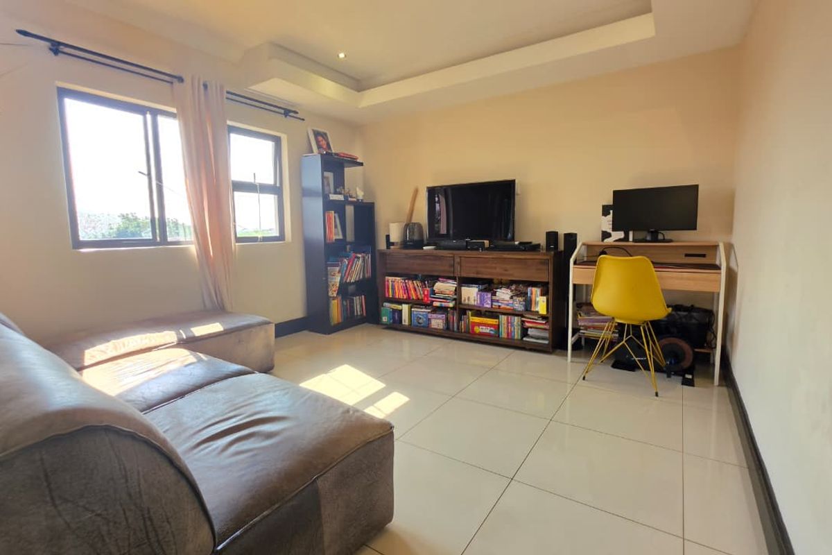 A functional living room featuring tiled flooring and a recessed ceiling design, providing a versatile space for relaxation or home office use.