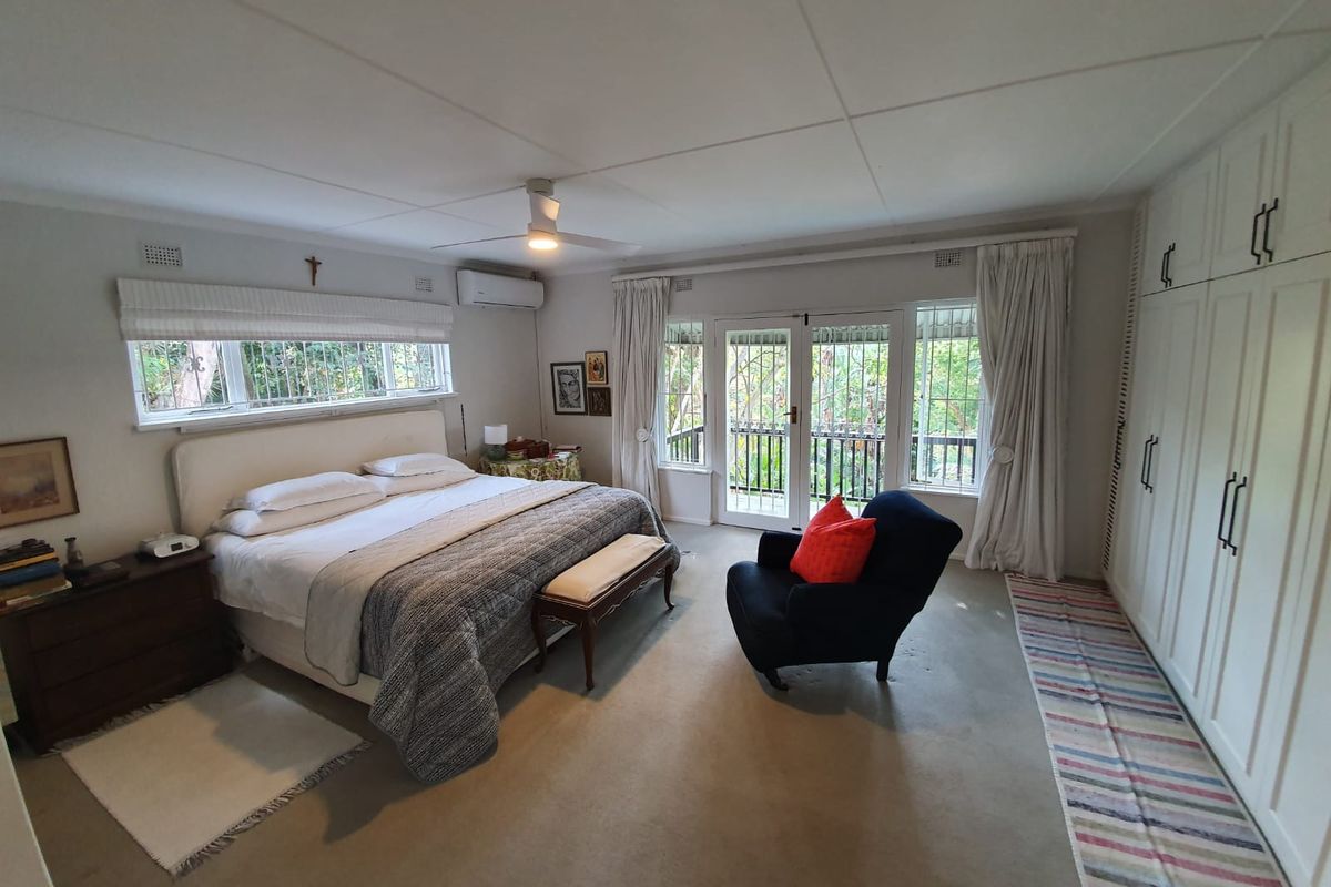 Spacious bedroom featuring built-in wardrobes, a ceiling fan, air conditioning unit, and direct access to a private balcony through glass doors.