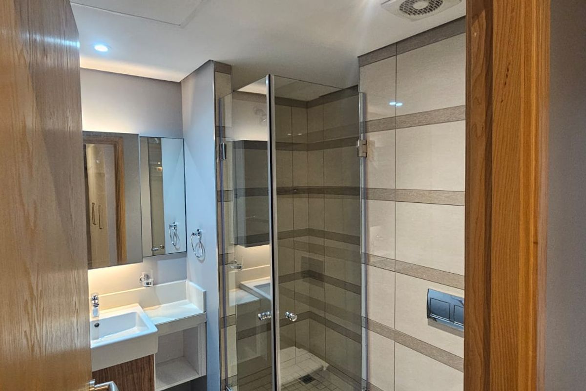 Modern bathroom featuring a glass-enclosed shower, wall-mounted toilet with concealed cistern, and a vanity basin with integrated storage.
