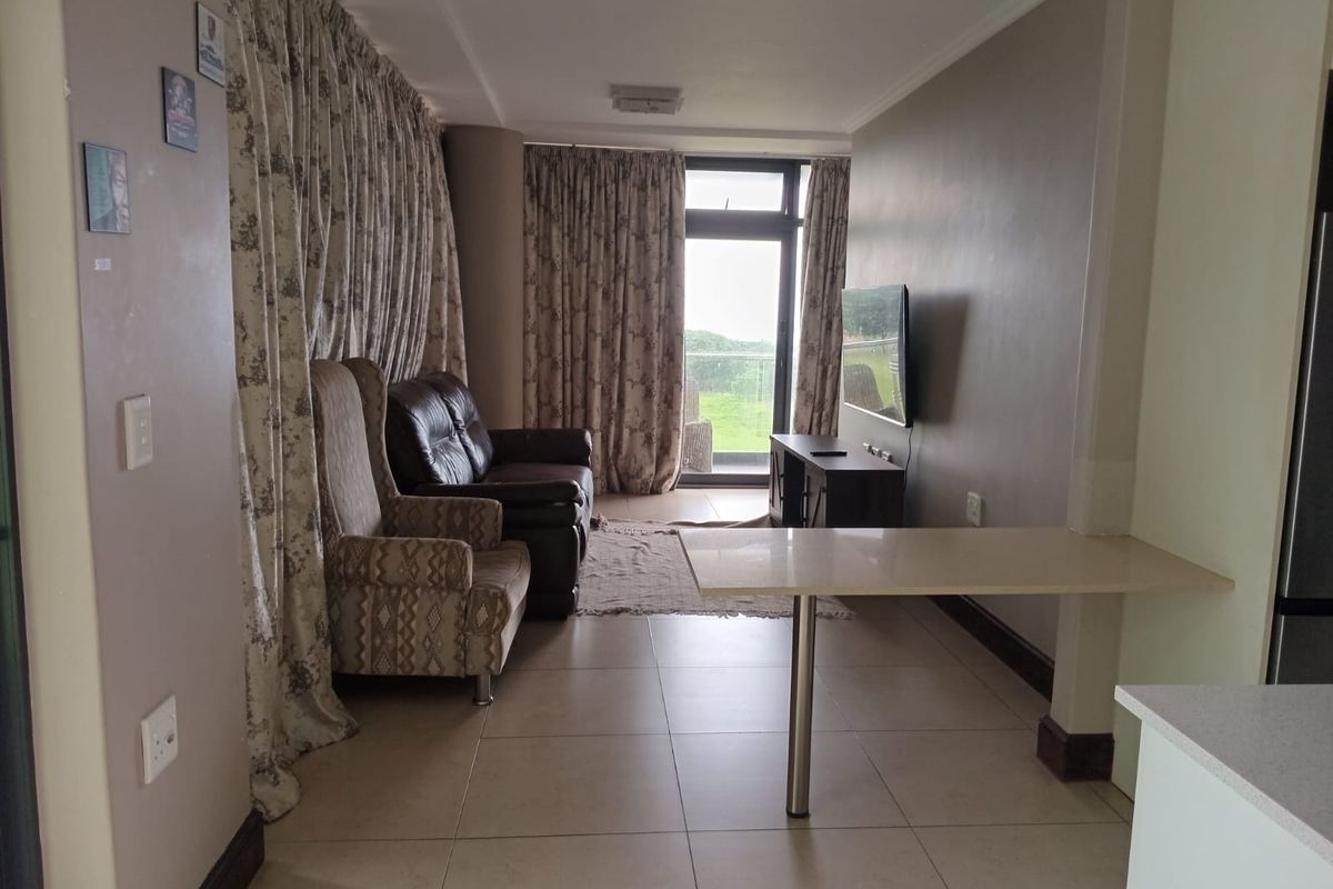 Open plan living area featuring tiled flooring, a breakfast bar, and a sliding glass door leading to an outdoor balcony.