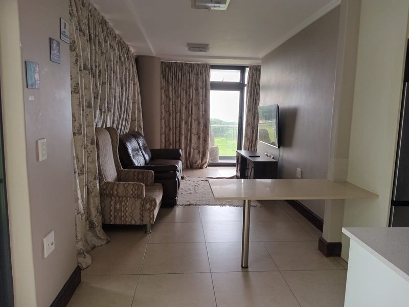 Open plan living area featuring tiled flooring, a breakfast bar, and a sliding glass door leading to an outdoor balcony.