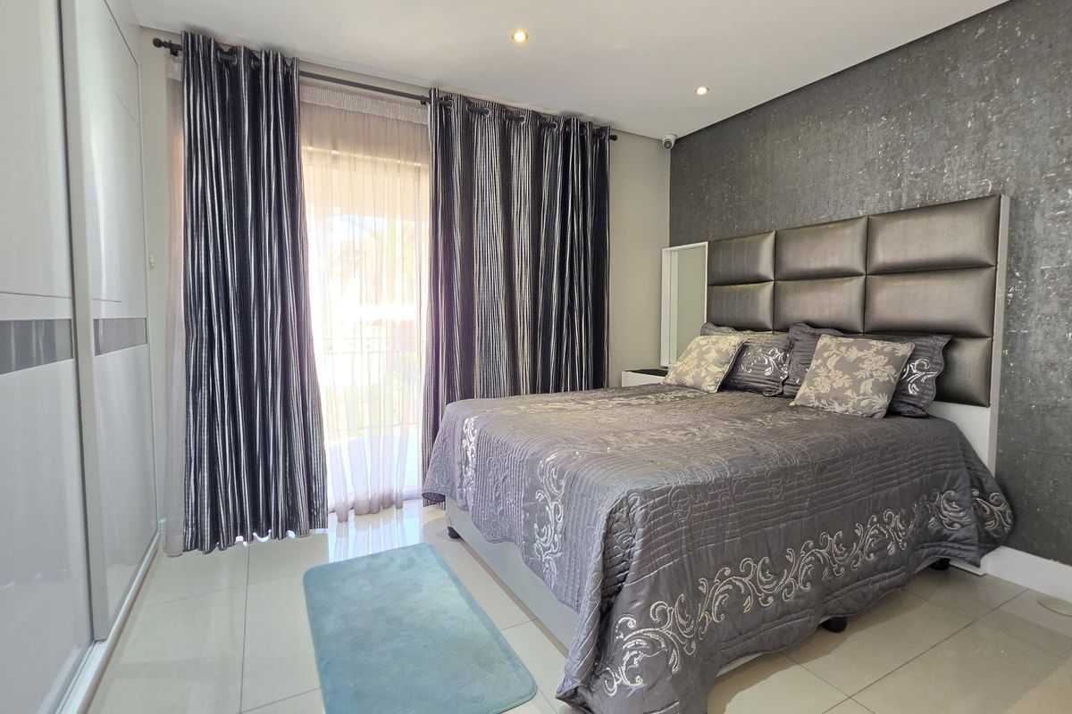 A well-maintained bedroom featuring built-in cupboards, tiled flooring, recessed ceiling lighting, and a feature wall with an integrated headboard.