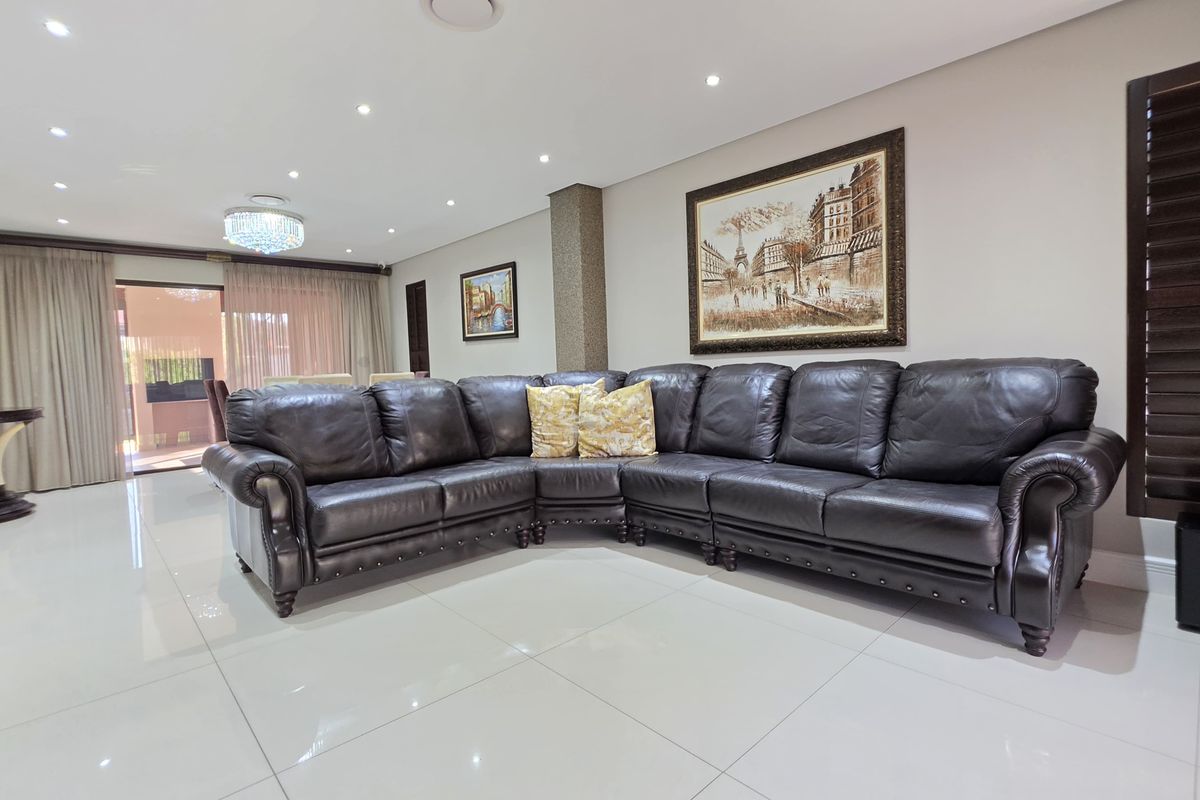 Spacious living area featuring polished porcelain floor tiles, recessed downlighting, and large sliding glass doors leading to an outdoor patio.