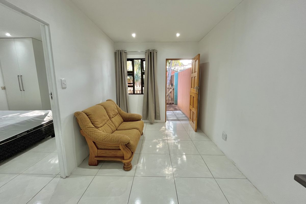 A bright living area featuring tiled flooring, recessed ceiling lighting, and direct access to an outdoor space.