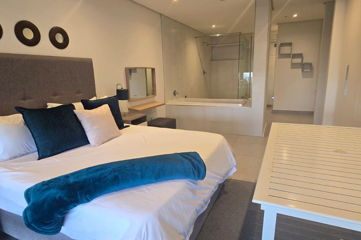 Spacious bedroom featuring an integrated en-suite bathroom with a glass-enclosed shower and bathtub, finished with modern tiling and built-in cabinetry.