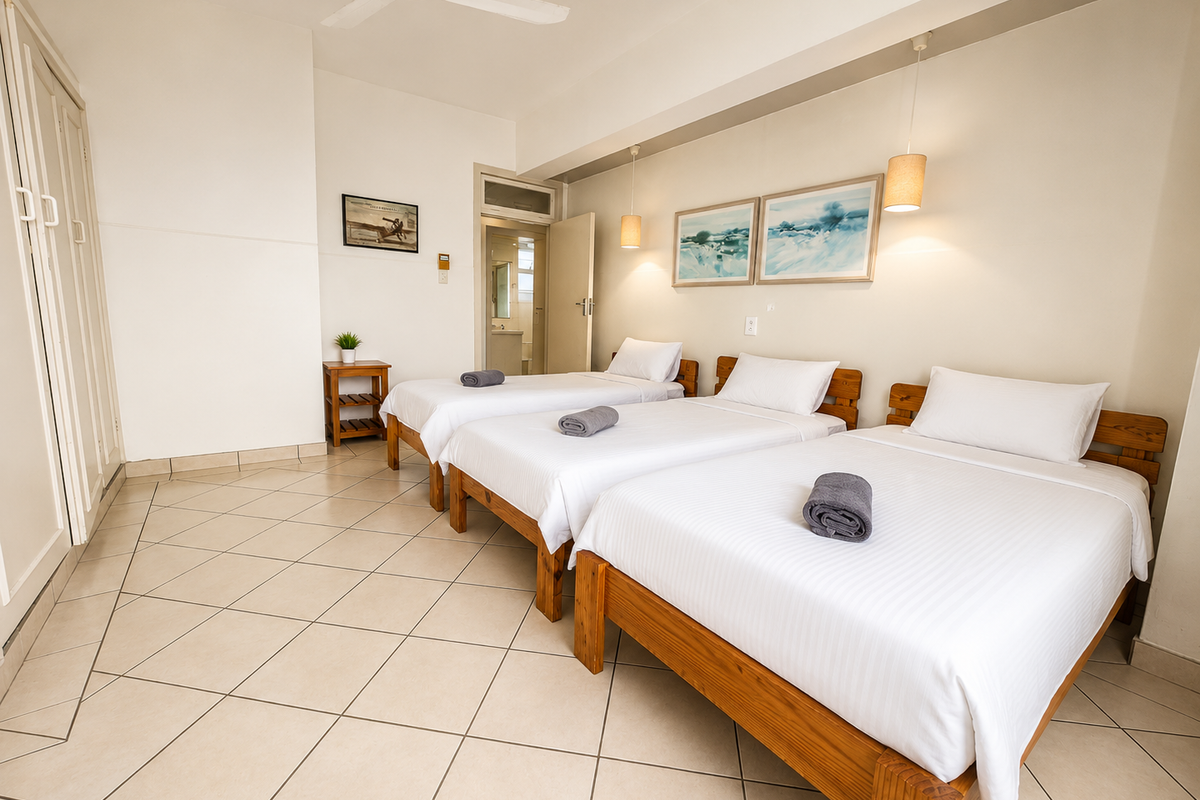 Spacious bedroom featuring tiled flooring, built-in cupboards, and an en-suite bathroom access, providing a functional layout for multiple occupants.
