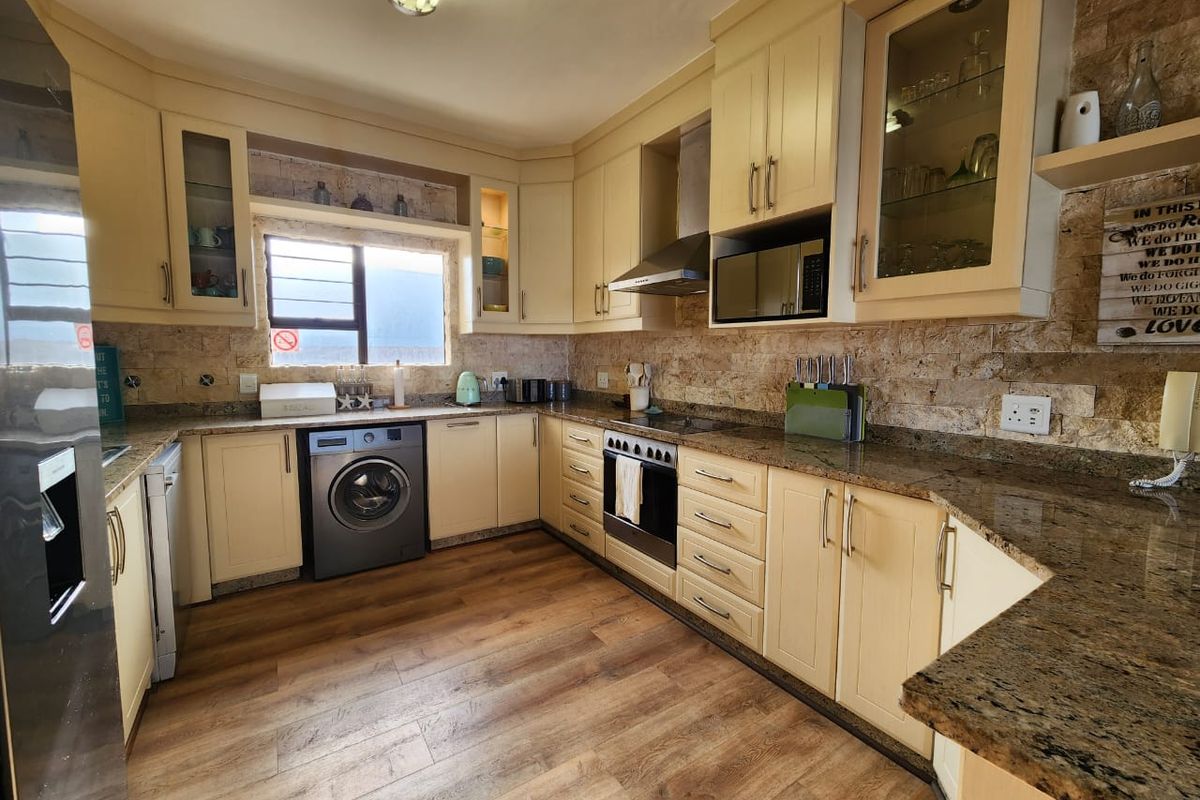 A functional kitchen featuring light-toned cabinetry, granite countertops, a stone tile backsplash, and integrated appliances including a stove and extractor fan.