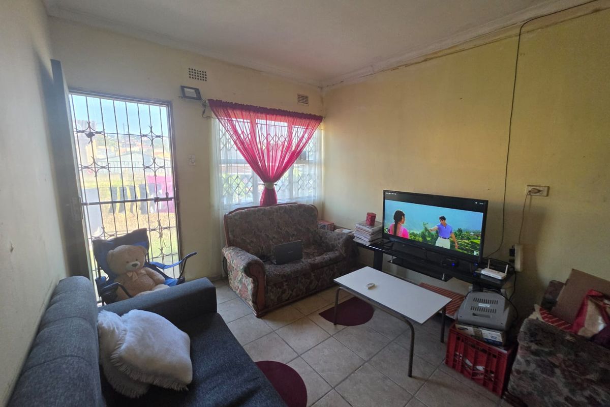 A living room featuring tiled flooring, security gate access, and a window with security bars, offering a functional space for relaxation.