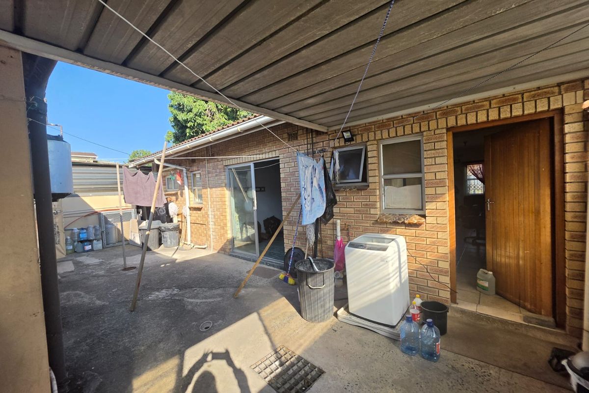 A functional rear courtyard area featuring a covered patio, concrete flooring, and direct access to the home's interior and laundry utility space.