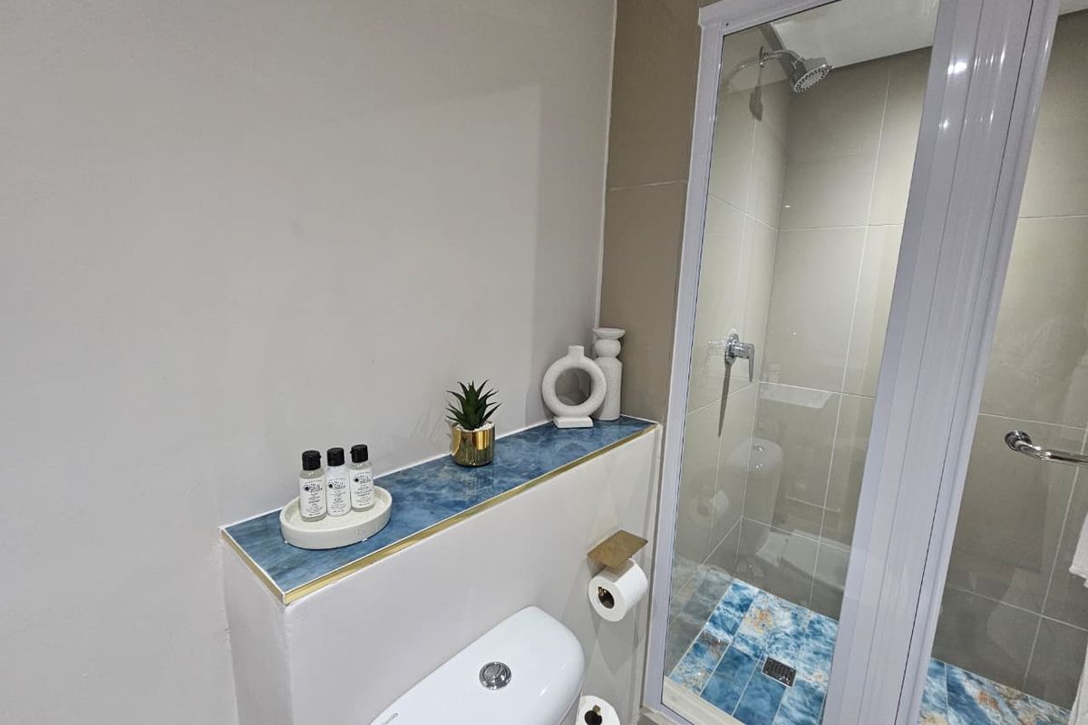 A modern bathroom featuring a glass-enclosed shower with decorative blue tiled flooring and a built-in vanity ledge with matching blue tile accents.