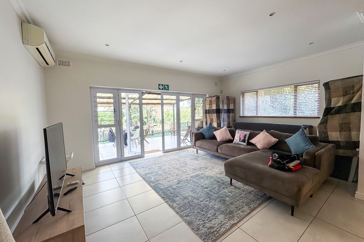 Spacious living room featuring tiled flooring, recessed lighting, and large sliding doors providing seamless access to the outdoor patio area.