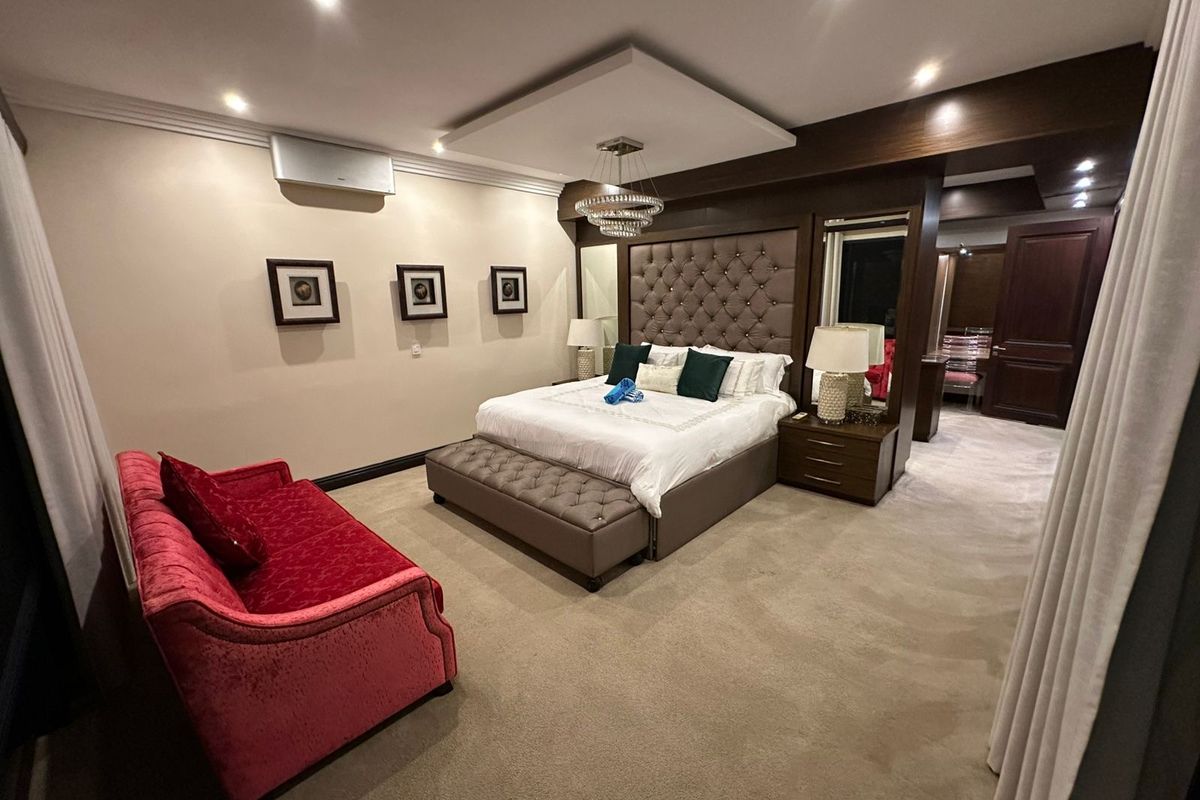 Spacious master bedroom featuring a tufted headboard, recessed ceiling lighting, integrated cabinetry, and an en-suite entrance.