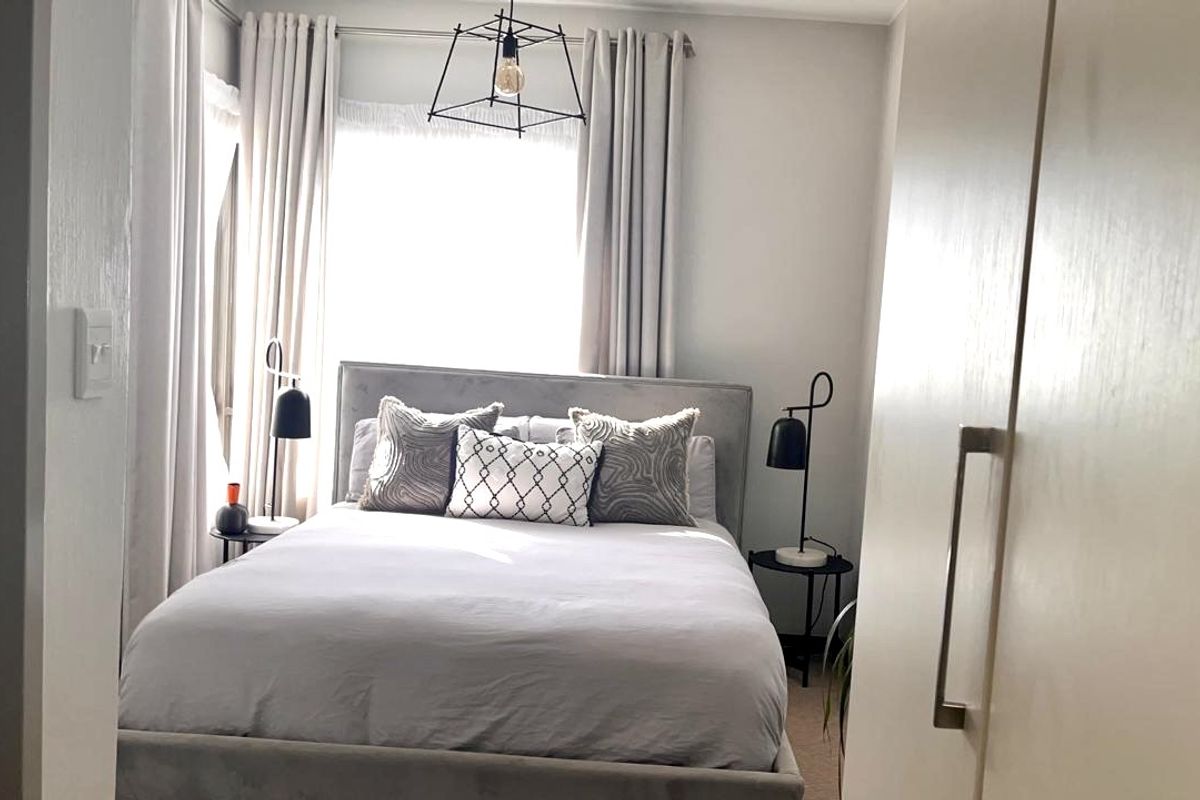 A cozy bedroom featuring a built-in wardrobe and natural light through window treatments.