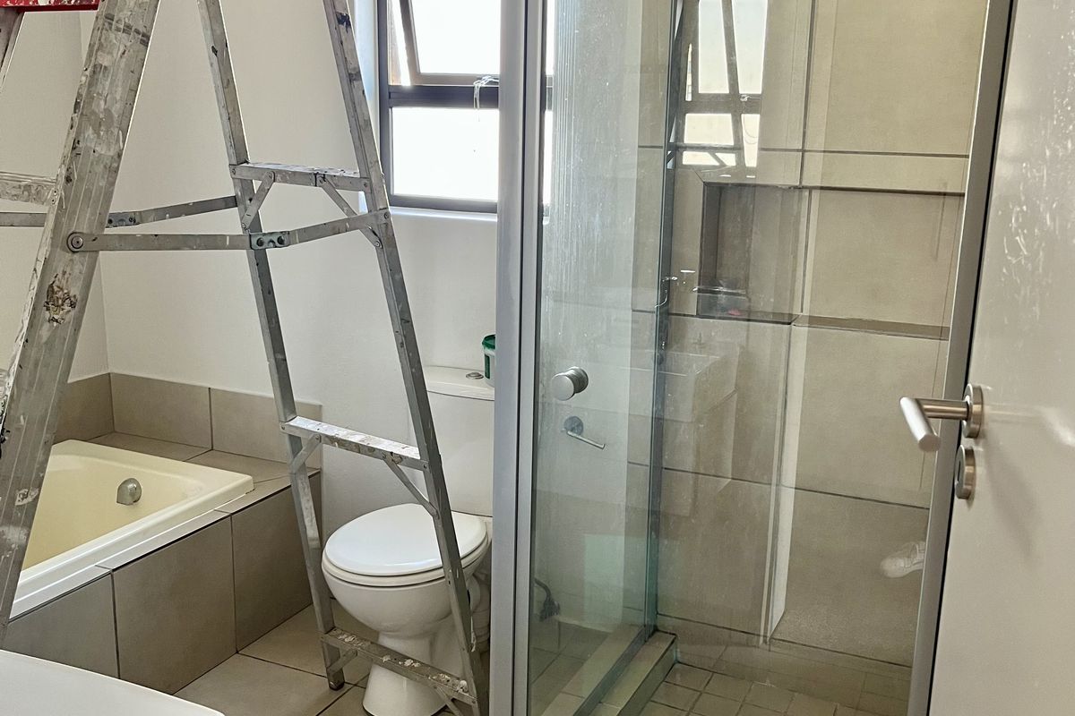 Bathroom featuring a tiled shower enclosure, built-in bathtub, toilet, and vanity basin with neutral floor and wall tiling.