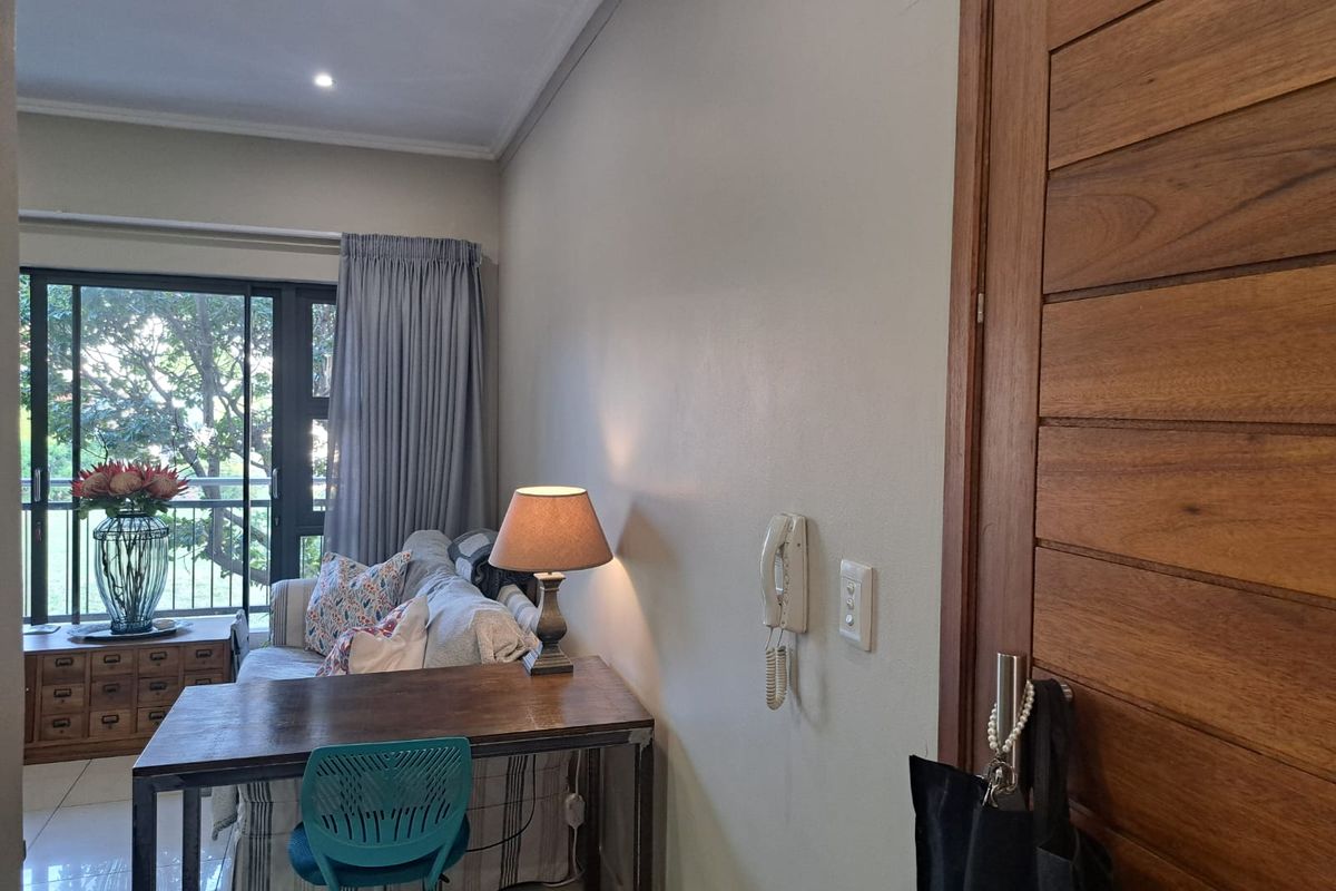 A view of the living area featuring a solid wood door, intercom system, and sliding glass doors leading to a balcony.