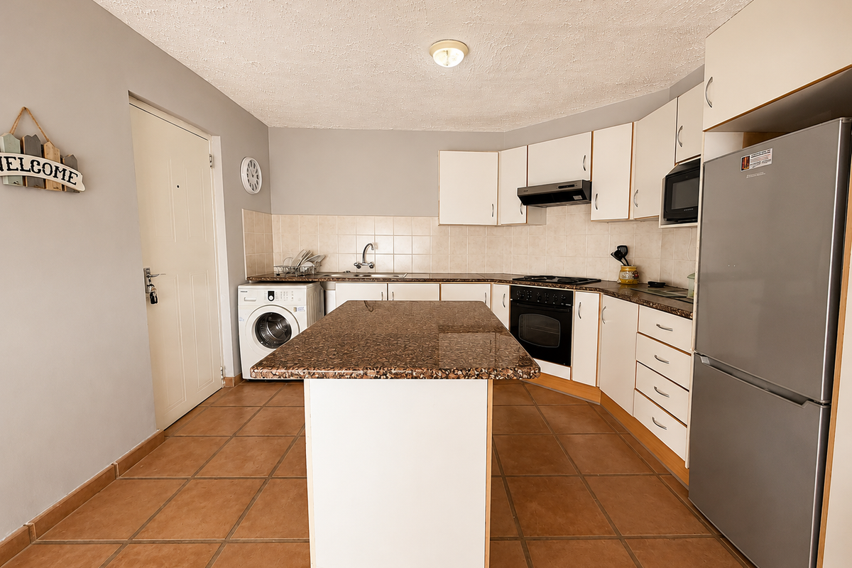 Functional kitchen featuring a central island, tiled flooring, built-in cabinetry, integrated oven, hob, and extractor fan with space for laundry appliances.