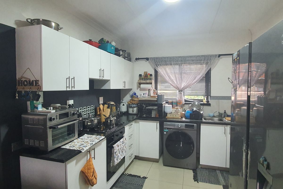 A functional kitchen featuring white cabinetry, dark countertops, a built-in oven, and an integrated laundry appliance space.