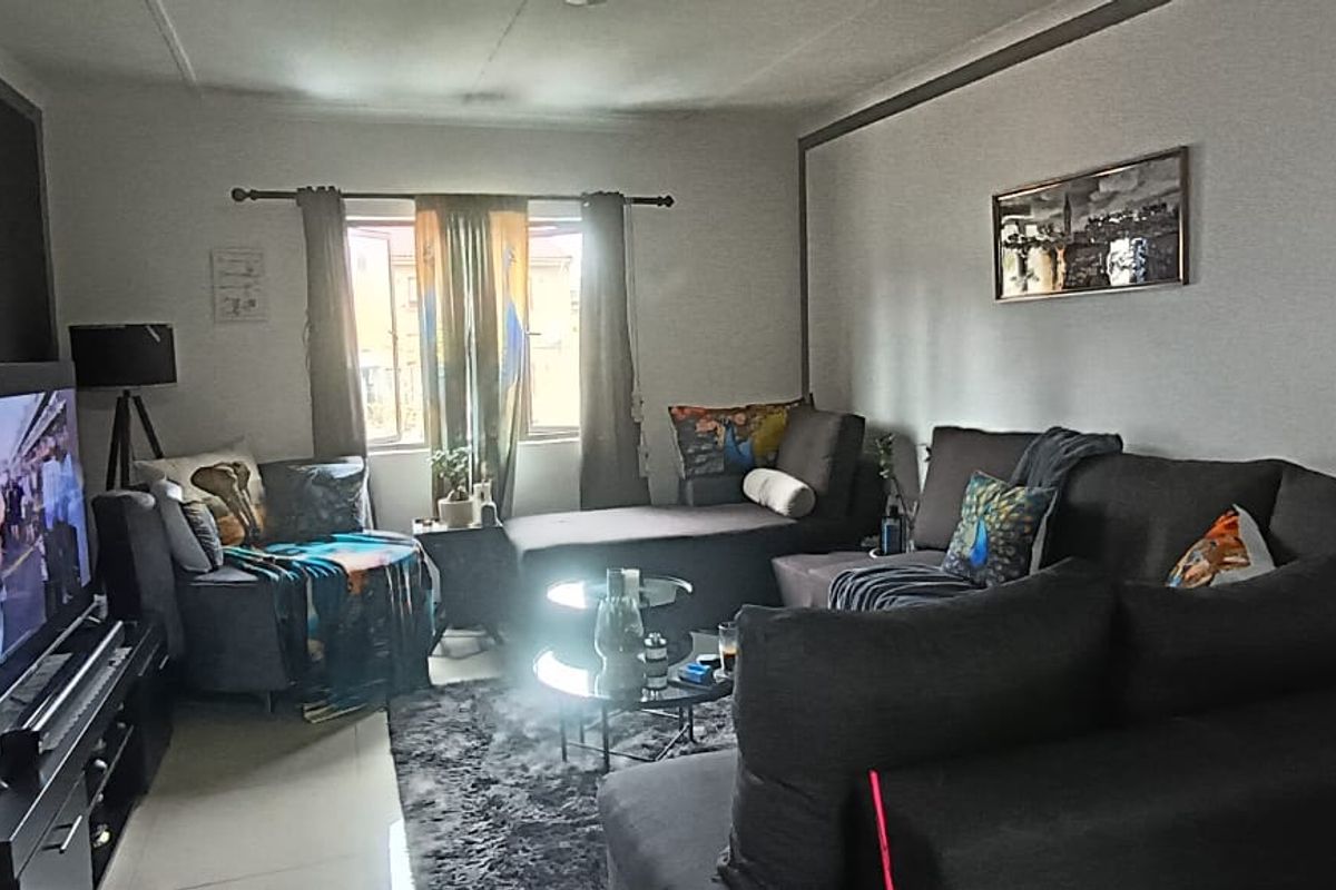 A comfortable living room featuring tiled flooring and natural light from the window, providing a functional space for relaxation.