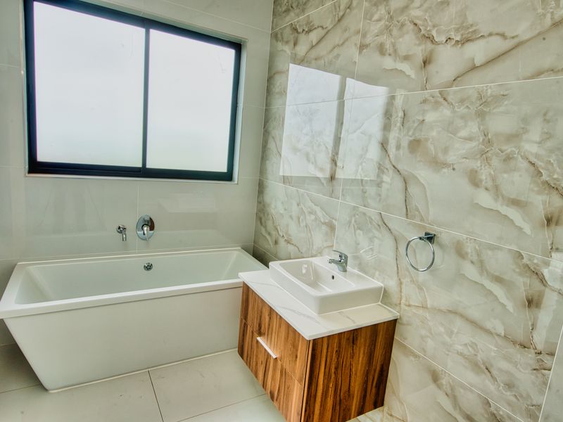 Modern bathroom featuring a built-in bathtub, wall-mounted vanity with basin, and elegant marble-look porcelain wall tiles.