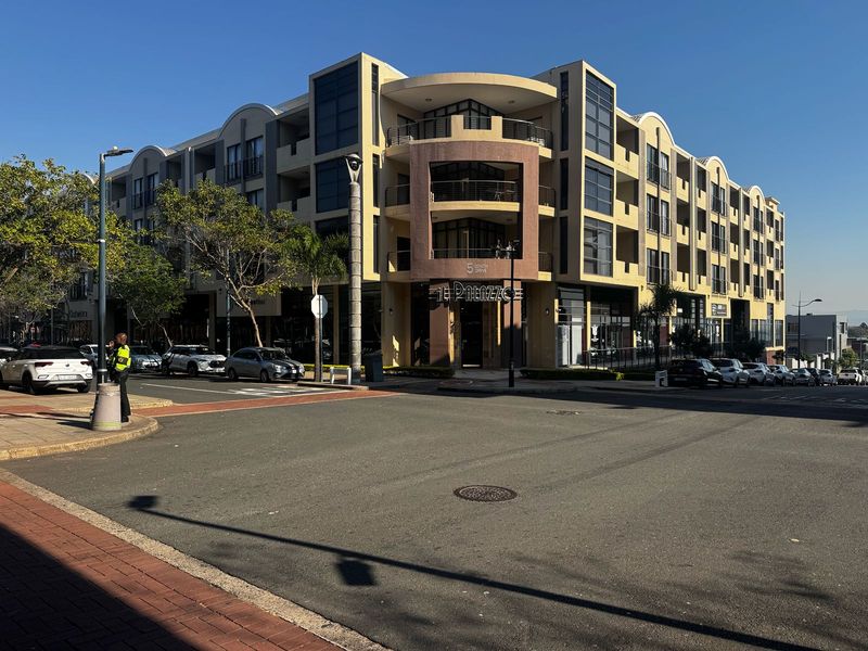 A clear street-level view of the multi-story apartment building facade, showcasing its architectural design and prominent corner entrance.