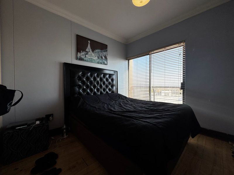 A bedroom featuring laminate flooring, coving, and venetian blinds, providing a functional space with natural light.
